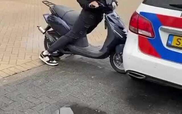 Scooterbink maakt een burn-out tegen een politieauto aan