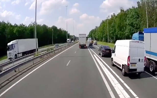 Automobilist bijna gesandwicht tussen vrachtwagens bij invoegen op de snelweg