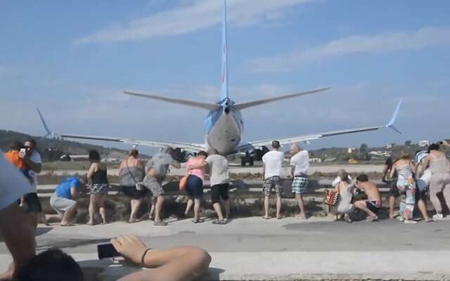 Toeristen laten zich vrijwillig zandstralen achter een Boeing op het Griekse eiland Skiathos