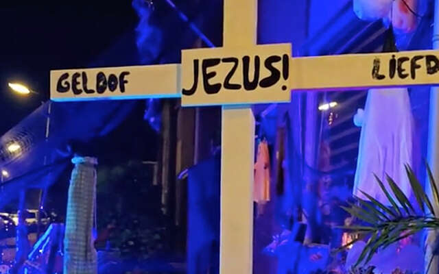 Boze gelovigen plaatsen Jezus-kruis in een voortuin die versierd is voor Halloween