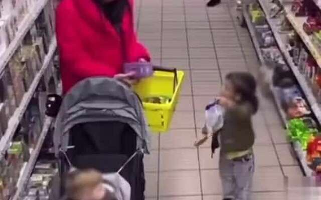 Moeder hangt ff het kind uit in de supermarkt